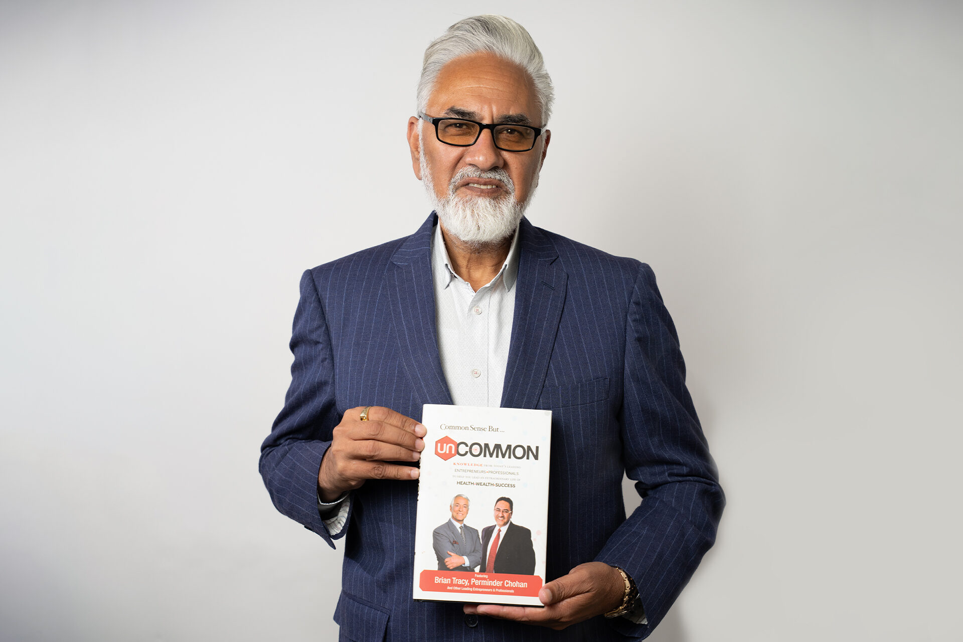 Perminder Chohan holding Uncommon, co-authored with Brian Tracy
